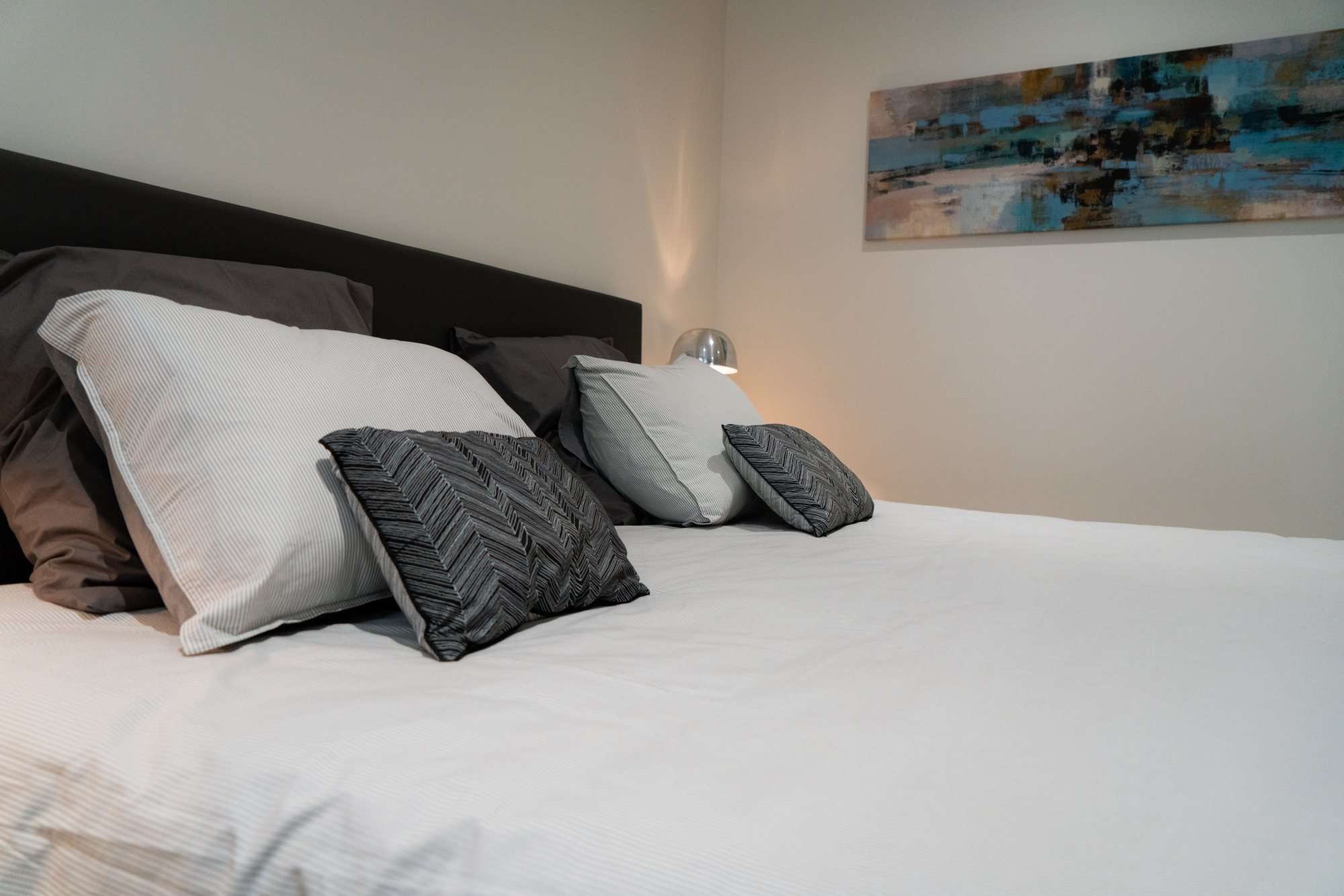 Le lit boxspring et ses coussins, un tableau au mur