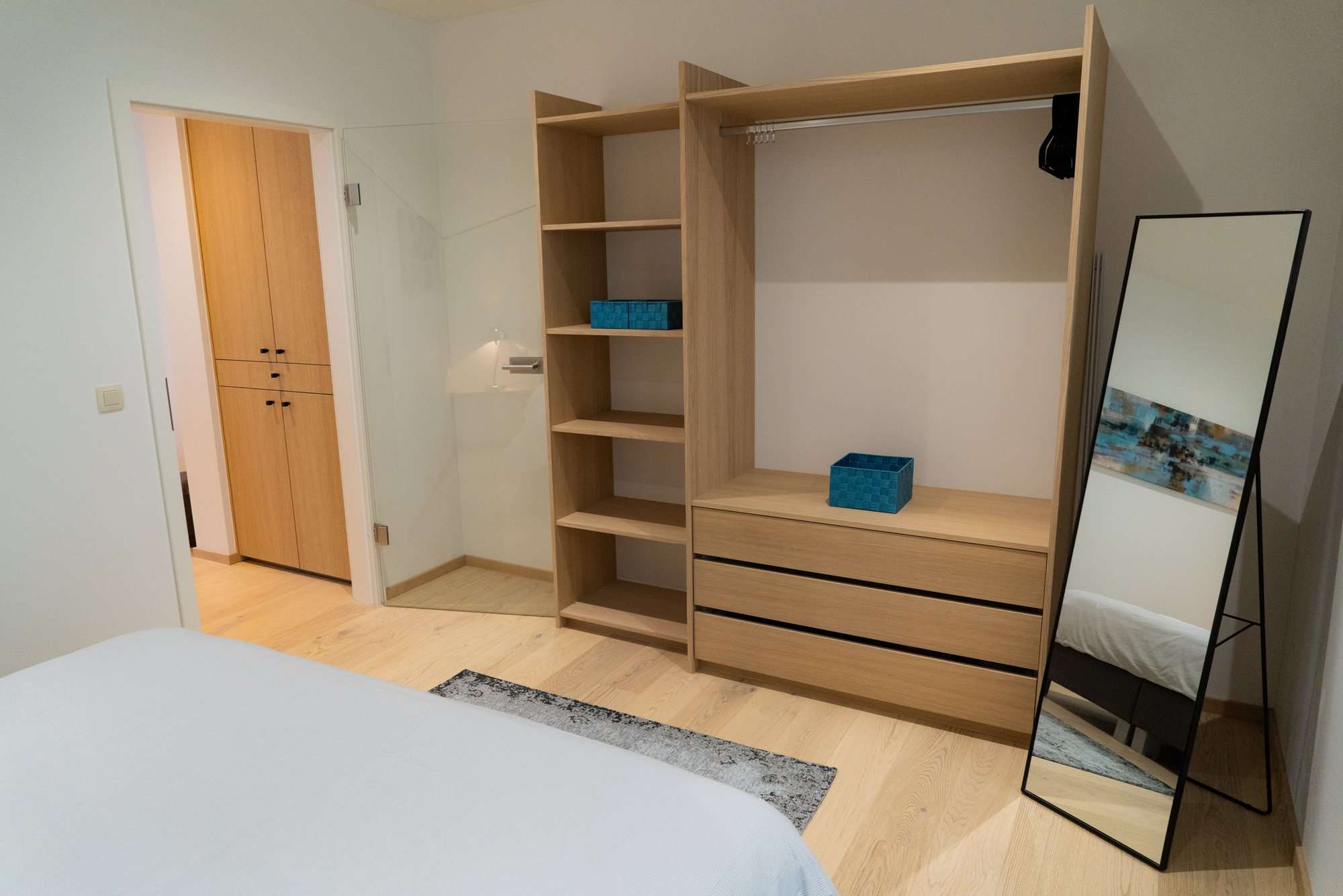 Penderie ouverte, étagères, commode et grand miroir dans la chambre