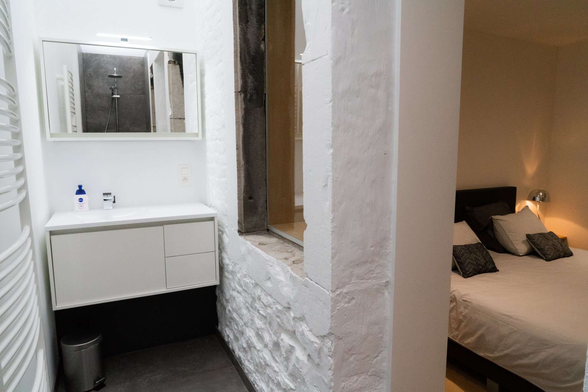La salle d'eau avec lavabo et douche à l'italienne, ouverte sur la chambre