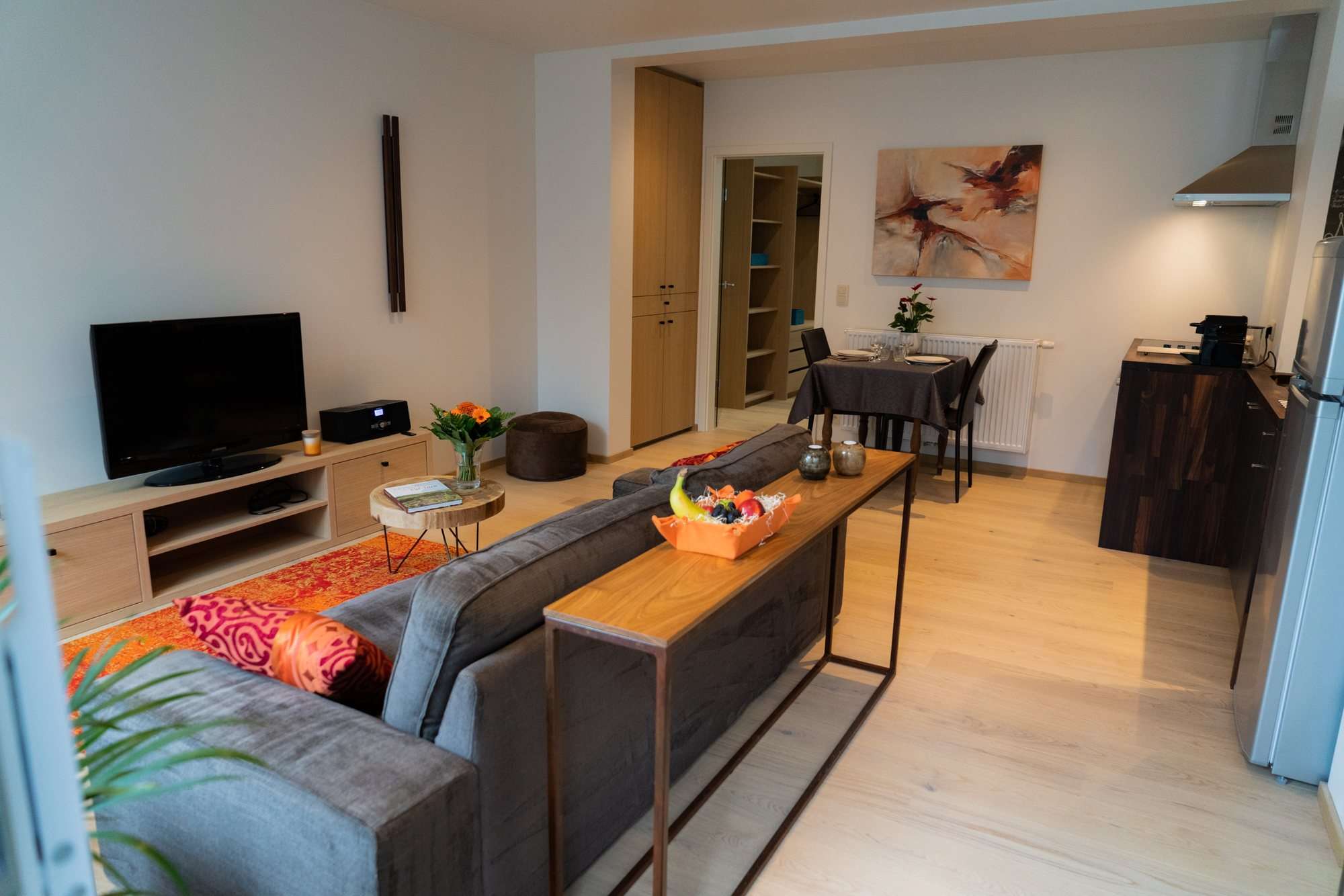 Salon avec canapé, télévision et coin repas, parquet clair